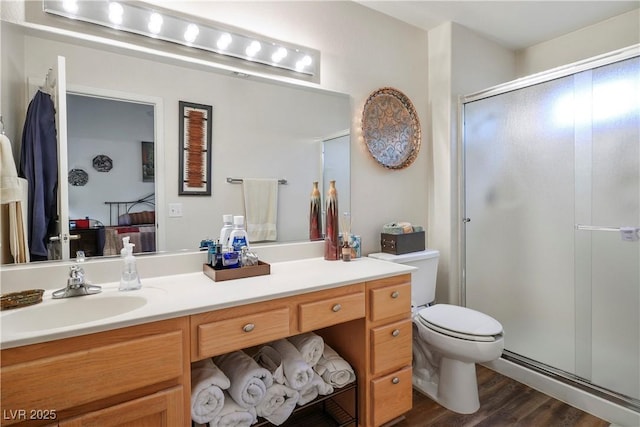 bathroom featuring vanity, hardwood / wood-style floors, a shower with door, and toilet