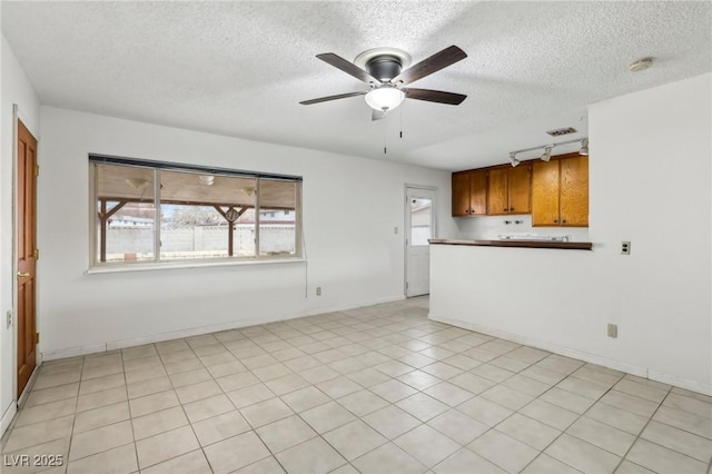 unfurnished living room with rail lighting, a textured ceiling, and ceiling fan