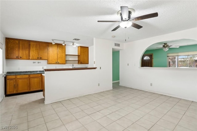 kitchen featuring ceiling fan, rail lighting, light tile patterned floors, and a textured ceiling