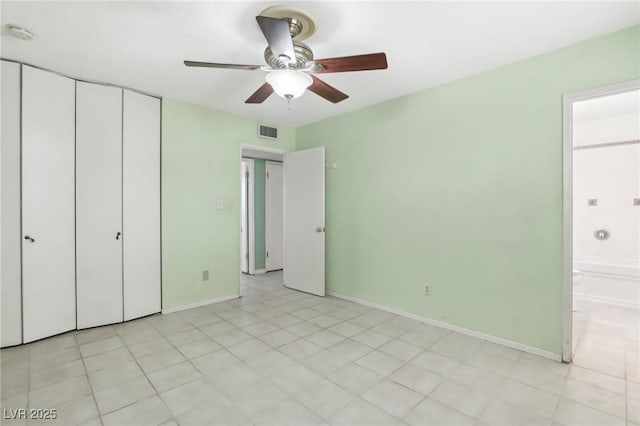 unfurnished bedroom with light tile patterned flooring, ensuite bath, ceiling fan, and a closet