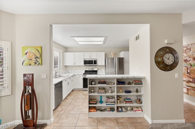 kitchen with white cabinetry, sink, light tile patterned flooring, and appliances with stainless steel finishes