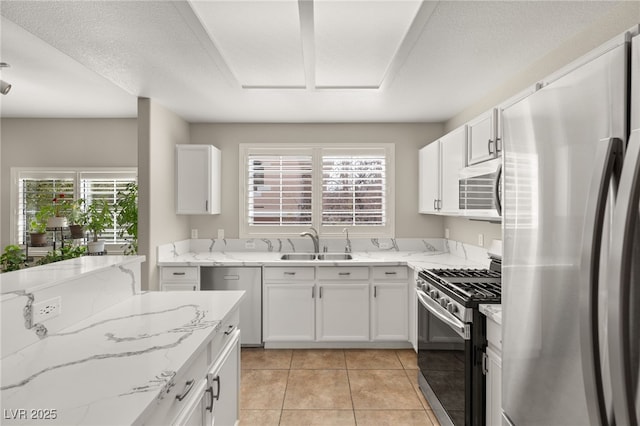 kitchen featuring sink, light tile patterned floors, appliances with stainless steel finishes, light stone countertops, and white cabinets