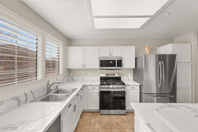 kitchen with appliances with stainless steel finishes, light stone countertops, sink, and white cabinets