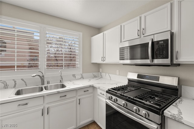 kitchen featuring a wealth of natural light, sink, white cabinets, light stone counters, and stainless steel appliances