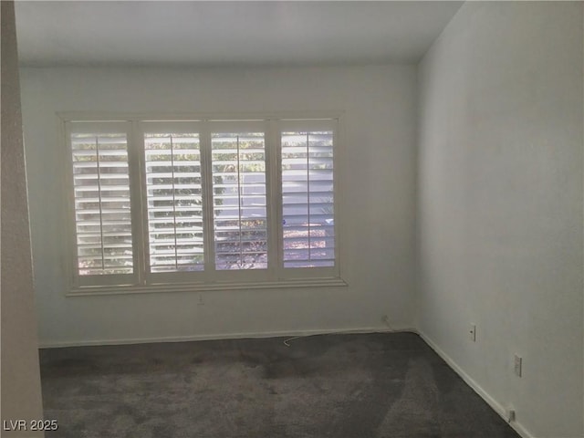 unfurnished room featuring dark colored carpet and plenty of natural light