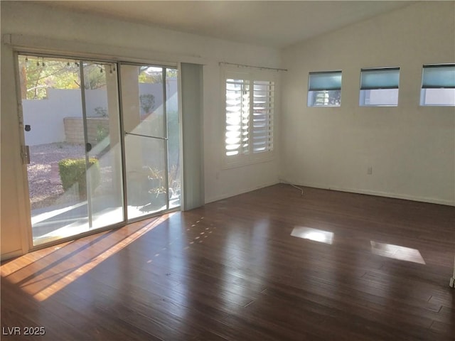 spare room with lofted ceiling, a healthy amount of sunlight, and dark hardwood / wood-style floors