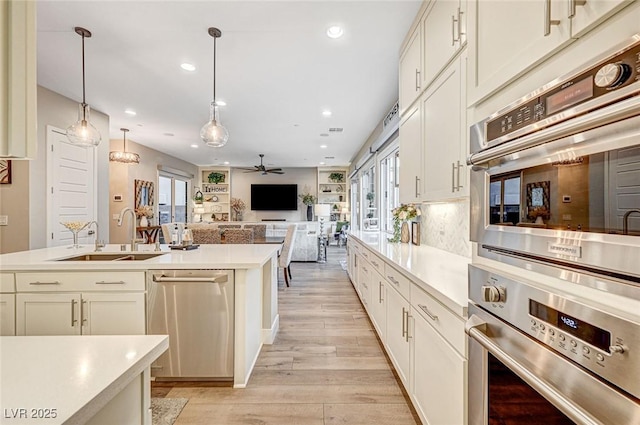 kitchen featuring stainless steel appliances, hanging light fixtures, sink, and a wealth of natural light