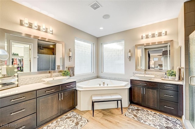 bathroom featuring hardwood / wood-style flooring, vanity, and separate shower and tub