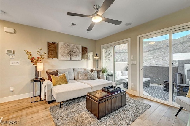 living room featuring plenty of natural light, ceiling fan, and light hardwood / wood-style flooring