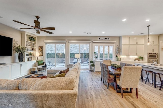 living room with ceiling fan, a healthy amount of sunlight, and light wood-type flooring