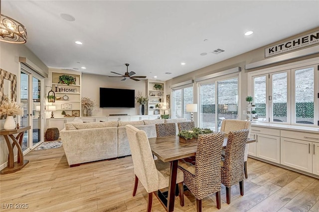 dining room with built in shelves, light hardwood / wood-style flooring, and ceiling fan