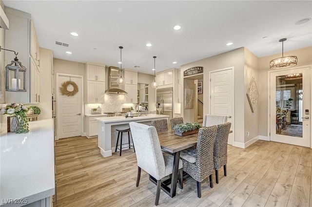 dining area with sink, a chandelier, and light hardwood / wood-style floors