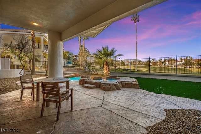 patio terrace at dusk with a fenced in pool