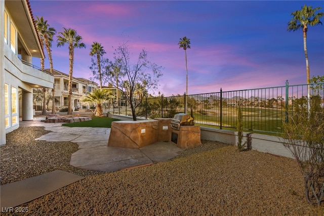 yard at dusk with exterior kitchen and a patio