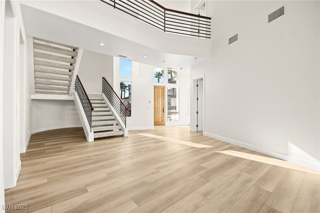 unfurnished living room featuring light hardwood / wood-style floors and a high ceiling