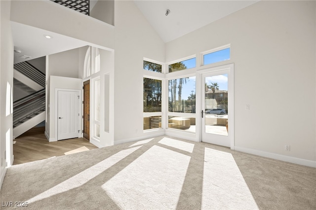 unfurnished bedroom with light carpet, access to exterior, and high vaulted ceiling