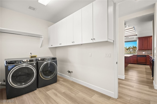 laundry room with cabinets, washer and dryer, and light hardwood / wood-style flooring