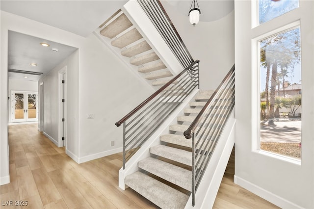 staircase with wood-type flooring and french doors