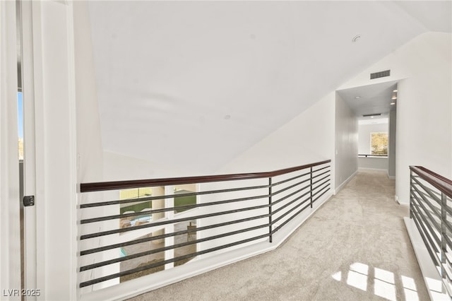 hallway with lofted ceiling and light carpet