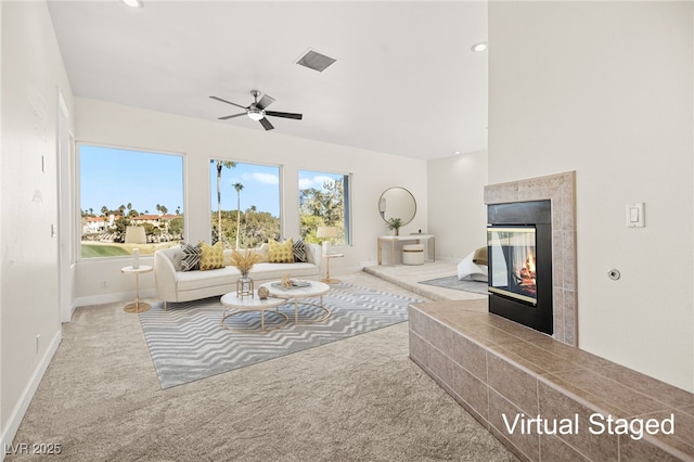 living room with a tiled fireplace, carpet flooring, and ceiling fan