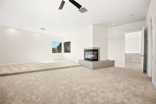 unfurnished living room with light carpet, a tile fireplace, and ceiling fan