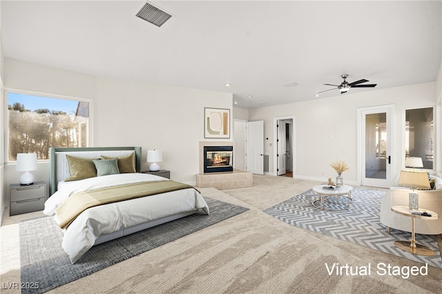 bedroom with access to outside, light colored carpet, and a tile fireplace