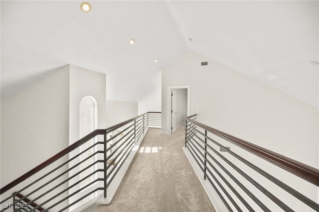 hallway featuring lofted ceiling and light carpet