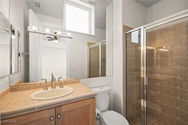 bathroom with a shower with door, vanity, and toilet