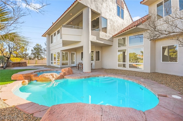 back of house with a pool with hot tub, a patio, and a balcony