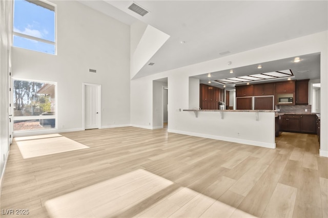 unfurnished living room featuring light hardwood / wood-style floors and a high ceiling