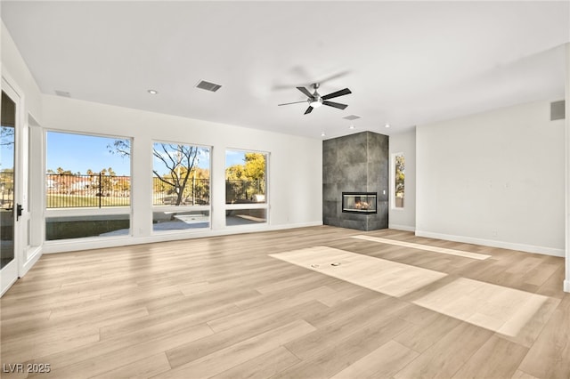 unfurnished living room with ceiling fan, a tile fireplace, and light hardwood / wood-style flooring