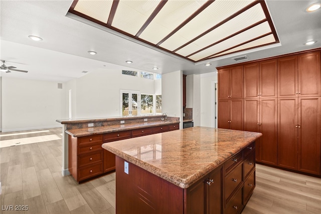 kitchen with light stone counters, a center island, and light hardwood / wood-style floors