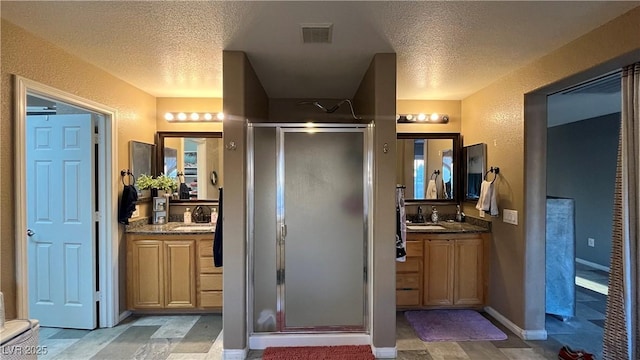 bathroom with vanity, a shower with door, and a textured ceiling