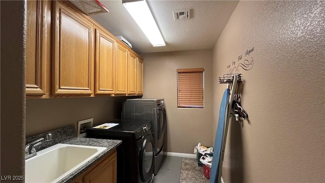 laundry area with cabinets, washer and clothes dryer, sink, and a textured ceiling