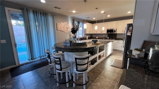 kitchen featuring pendant lighting, sink, white cabinetry, stainless steel appliances, and a center island