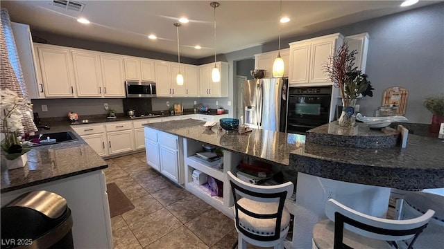 kitchen with pendant lighting, white cabinetry, a kitchen bar, a center island, and black appliances