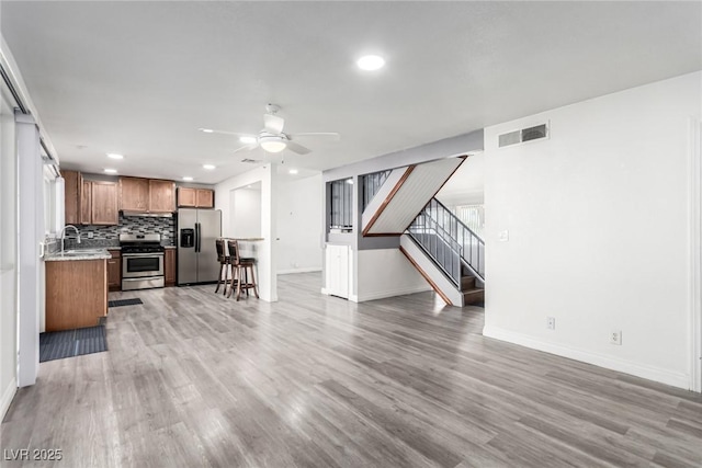 kitchen featuring light wood-type flooring, appliances with stainless steel finishes, sink, and backsplash