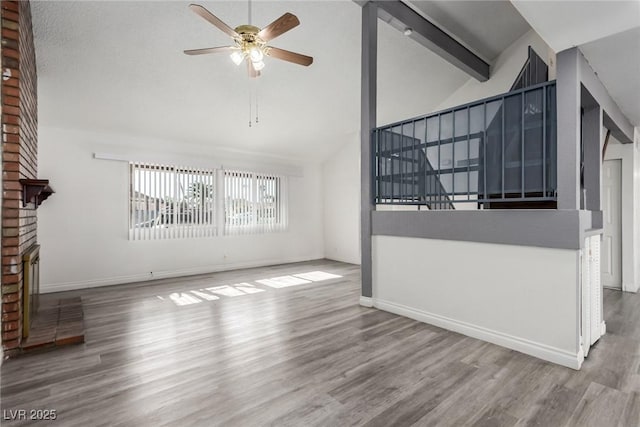 unfurnished living room with high vaulted ceiling, a fireplace, ceiling fan, light hardwood / wood-style floors, and beam ceiling