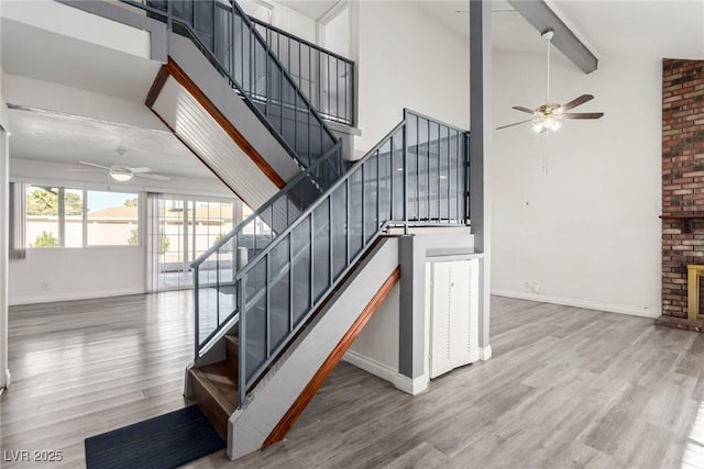 staircase with a high ceiling, hardwood / wood-style flooring, and a fireplace