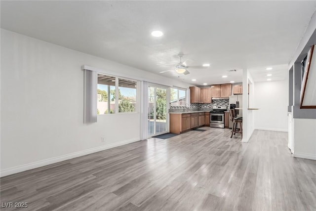 kitchen featuring sink, light hardwood / wood-style flooring, ceiling fan, stainless steel appliances, and tasteful backsplash