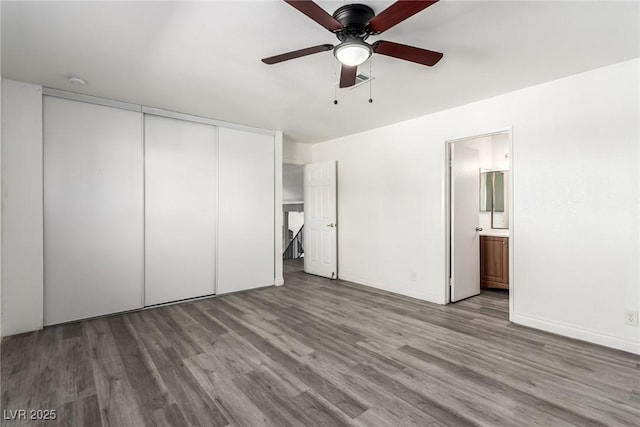 unfurnished bedroom with wood-type flooring, ceiling fan, ensuite bath, and a closet