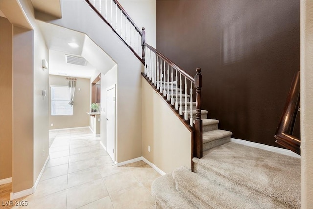 stairs with tile patterned flooring and a towering ceiling