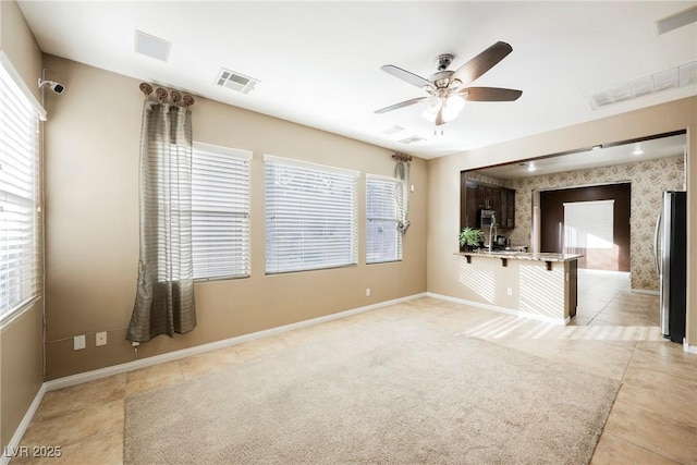 empty room with plenty of natural light, light colored carpet, and ceiling fan