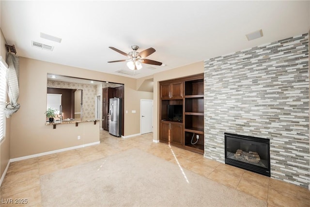 unfurnished living room with light tile patterned floors, a fireplace, sink, and ceiling fan