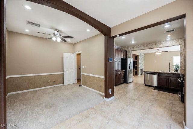 interior space featuring sink, light carpet, beamed ceiling, ceiling fan, and stainless steel appliances