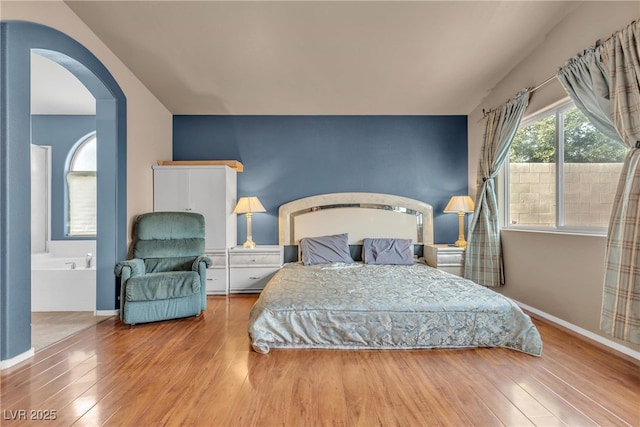 bedroom featuring hardwood / wood-style flooring and ensuite bath