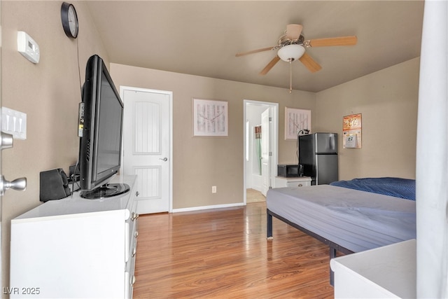 bedroom with light hardwood / wood-style floors, stainless steel refrigerator, and ceiling fan