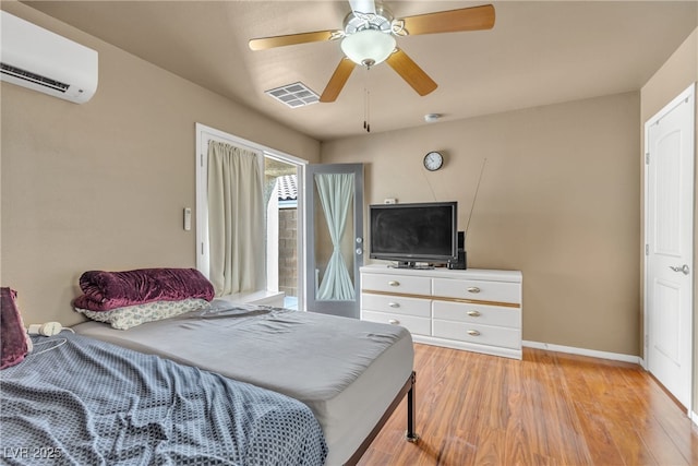 bedroom with ceiling fan, a wall unit AC, and light hardwood / wood-style flooring