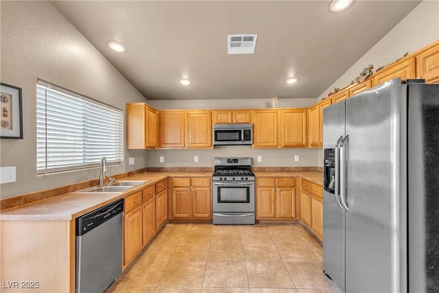 kitchen featuring sink, stainless steel appliances, light tile patterned flooring, light brown cabinetry, and vaulted ceiling