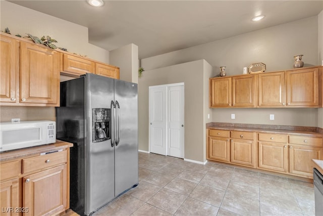 kitchen with light brown cabinetry, stainless steel appliances, and light tile patterned flooring